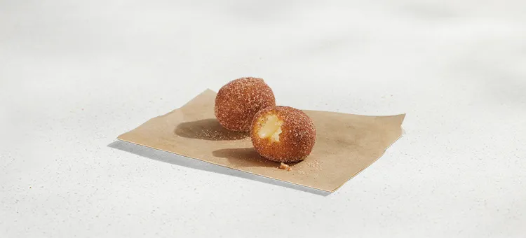 Cinnabon Delights® 2 Pack: Two warm donut holes dusted in cinnamon sugar and filled with Cinnabon® cream-cheese frosting.